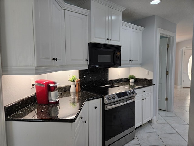 kitchen featuring white cabinetry, backsplash, dark stone counters, light tile patterned floors, and electric stove