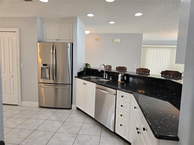 kitchen with sink, dark stone countertops, light tile patterned floors, appliances with stainless steel finishes, and white cabinets