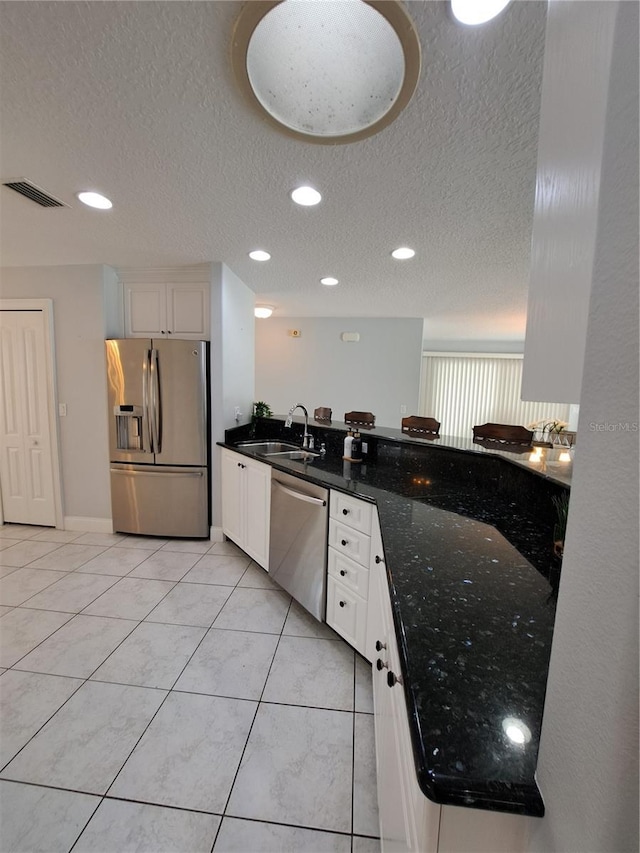 kitchen featuring sink, white cabinetry, a textured ceiling, dark stone countertops, and appliances with stainless steel finishes