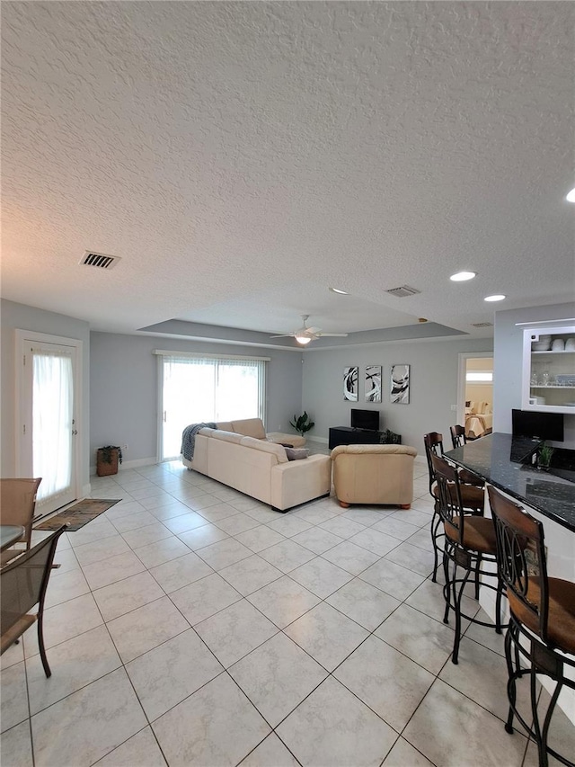 living room with light tile patterned floors, a textured ceiling, a healthy amount of sunlight, and ceiling fan