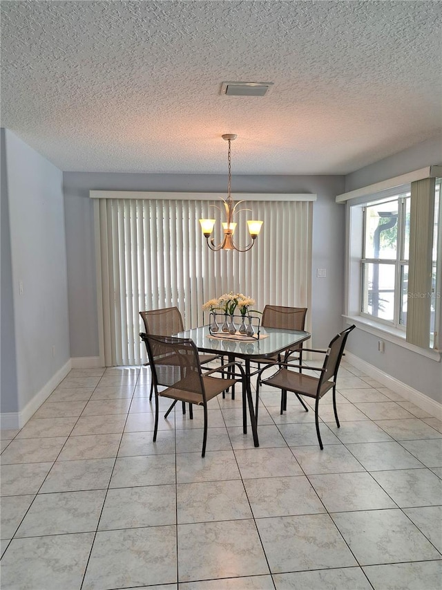 dining space featuring light tile patterned floors, a textured ceiling, and an inviting chandelier