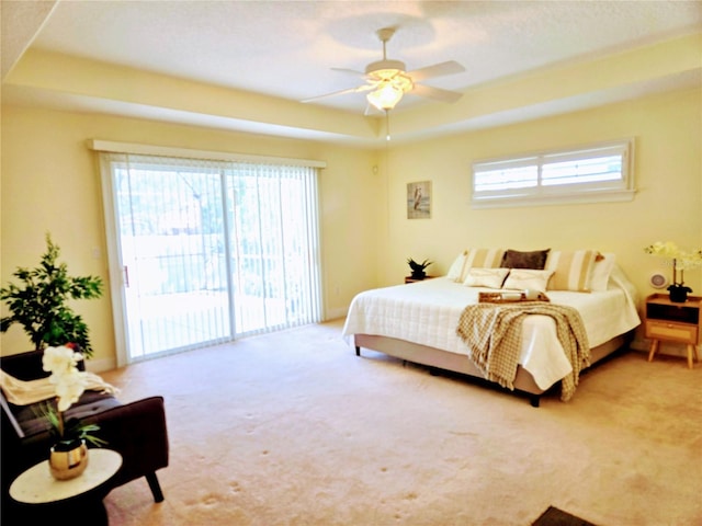 bedroom featuring ceiling fan, carpet flooring, a raised ceiling, and access to outside