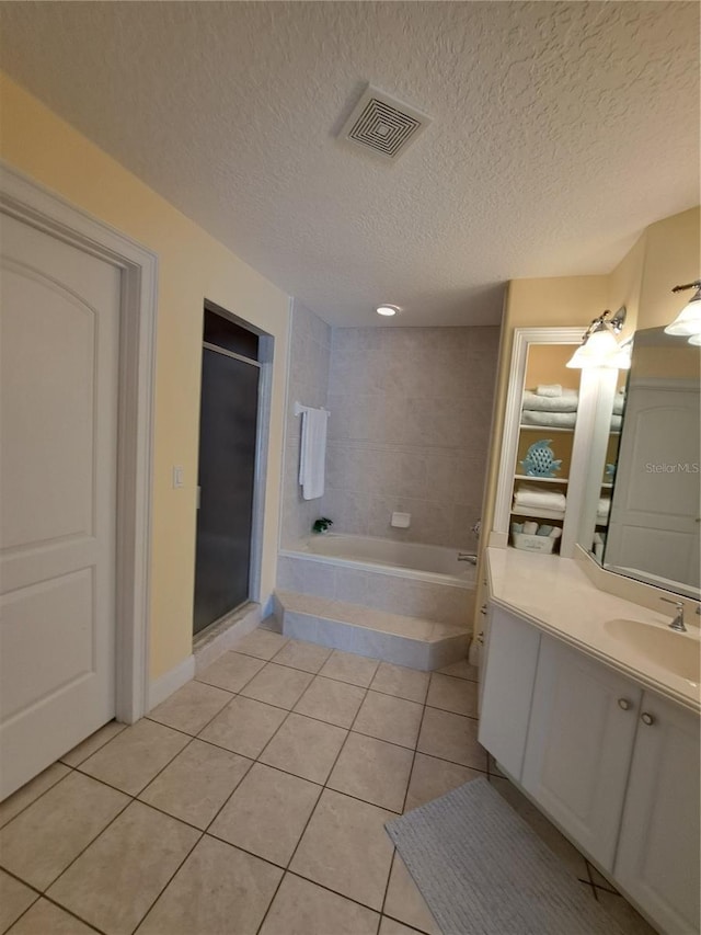 bathroom with independent shower and bath, vanity, tile patterned floors, and a textured ceiling