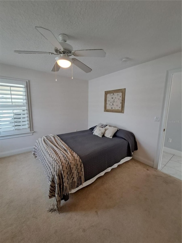 carpeted bedroom with ceiling fan and a textured ceiling