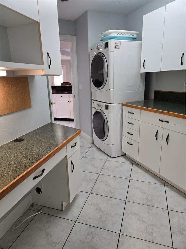 clothes washing area featuring cabinets and stacked washer and clothes dryer