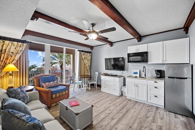 living room with beamed ceiling, ornamental molding, ceiling fan, a textured ceiling, and light wood-type flooring