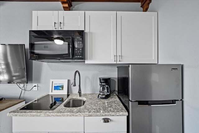 kitchen featuring white cabinetry, stainless steel fridge, and light stone counters