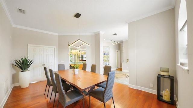 dining space with wood-type flooring and ornamental molding