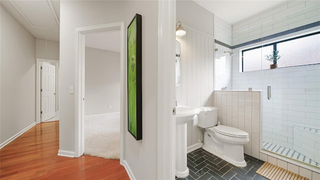 bathroom with wood-type flooring, toilet, and a shower with door