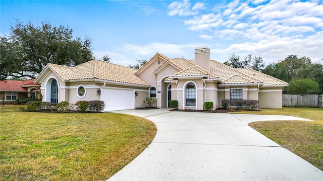 mediterranean / spanish-style house featuring a garage and a front lawn