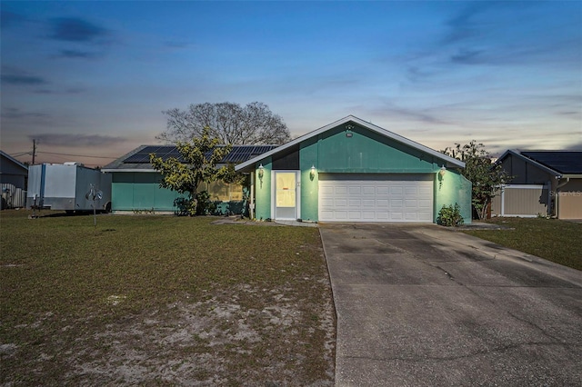 single story home featuring a garage, solar panels, and a yard