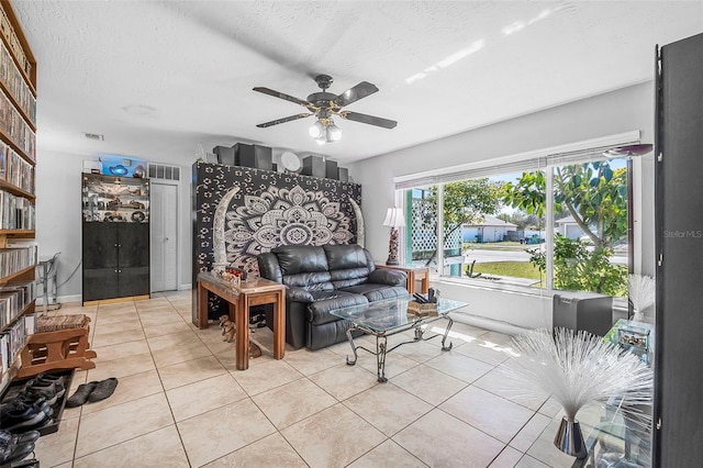 living room featuring ceiling fan, light tile patterned floors, and a textured ceiling