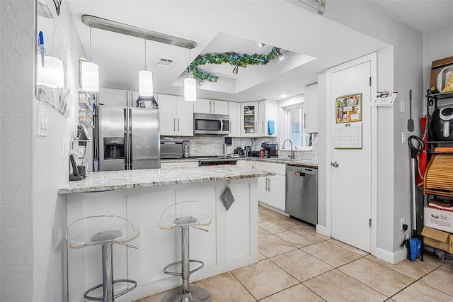 kitchen featuring white cabinetry, appliances with stainless steel finishes, and a breakfast bar area