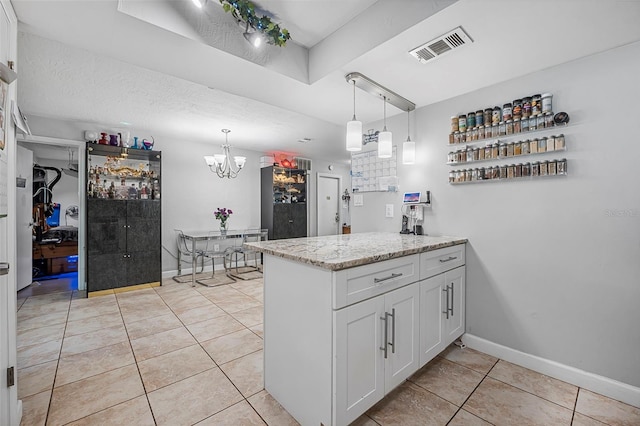 kitchen with hanging light fixtures, white cabinetry, light stone countertops, and light tile patterned floors