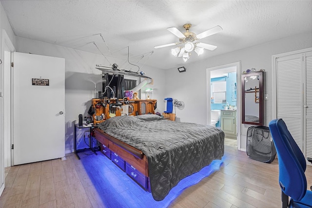 bedroom featuring hardwood / wood-style flooring, ceiling fan, ensuite bath, and a textured ceiling