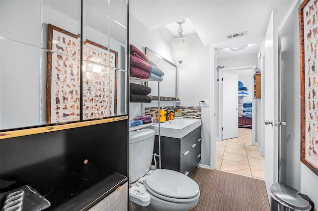 bathroom featuring tile patterned flooring, tasteful backsplash, vanity, and toilet