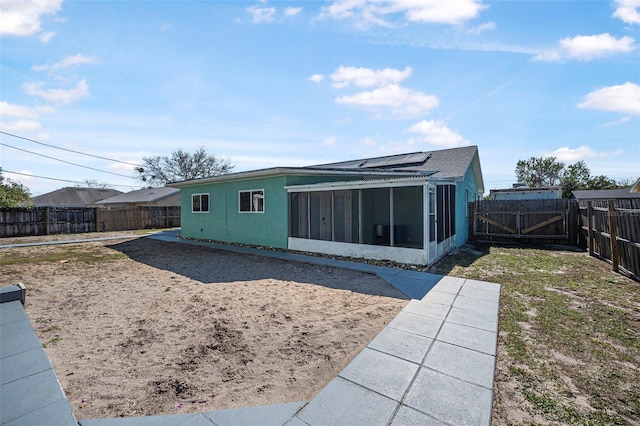 rear view of house featuring solar panels and a sunroom