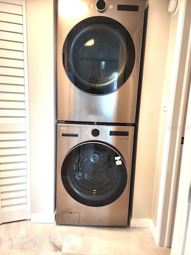 laundry area with laundry area, stacked washer and clothes dryer, and baseboards