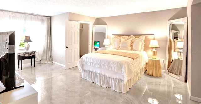 bedroom with baseboards, a textured ceiling, marble finish floor, and a fireplace