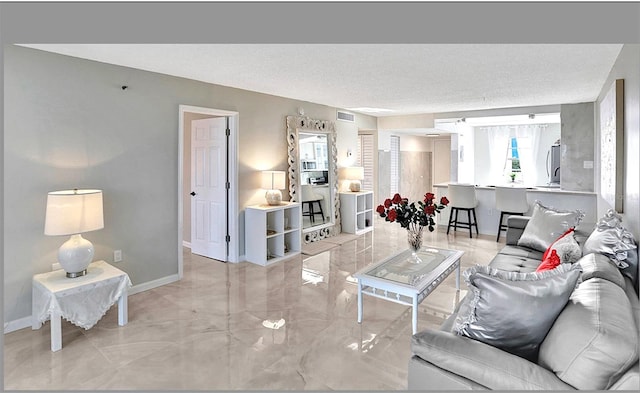 living area with baseboards, visible vents, and a textured ceiling