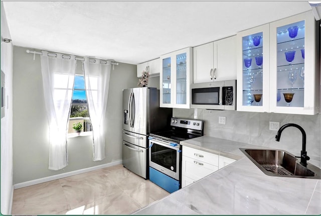 kitchen with white cabinetry, stainless steel appliances, glass insert cabinets, and a sink