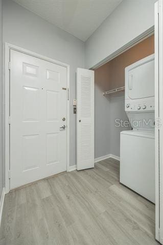 washroom featuring stacked washing maching and dryer and light wood-type flooring