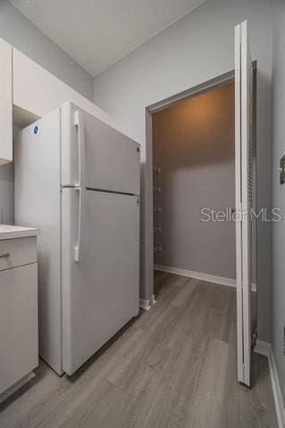 kitchen featuring white refrigerator, white cabinets, and light wood-type flooring