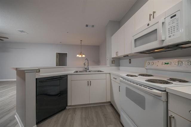 kitchen with sink, hanging light fixtures, kitchen peninsula, white appliances, and white cabinets