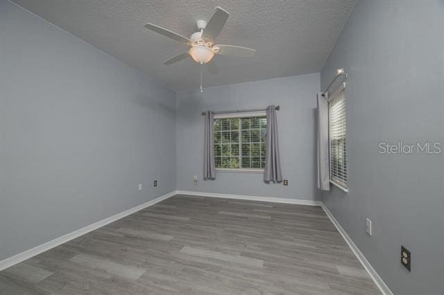 empty room with ceiling fan, hardwood / wood-style flooring, and a textured ceiling