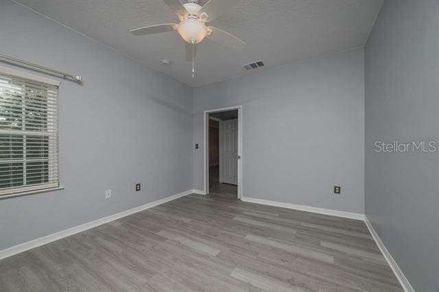 spare room with ceiling fan, a textured ceiling, and light hardwood / wood-style floors