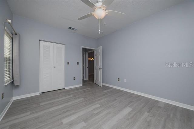 unfurnished bedroom with ceiling fan, light hardwood / wood-style floors, and a closet