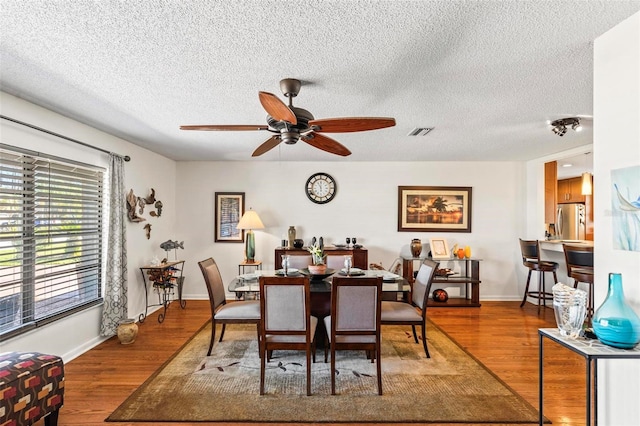 dining space featuring ceiling fan, wood-type flooring, and a textured ceiling