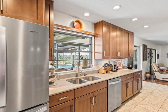 kitchen featuring light tile patterned floors, stainless steel appliances, backsplash, and sink