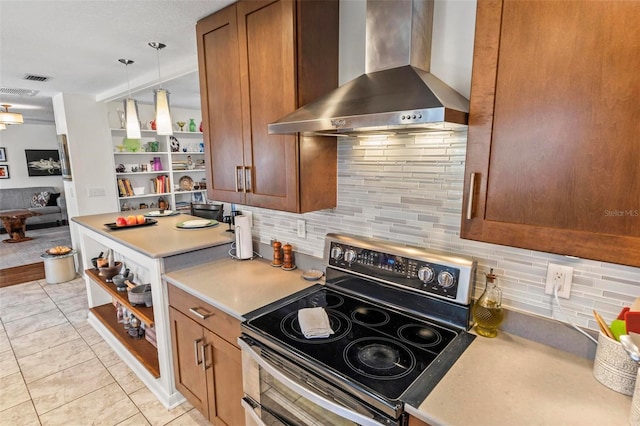 kitchen with light tile patterned floors, decorative light fixtures, wall chimney range hood, range with electric stovetop, and decorative backsplash