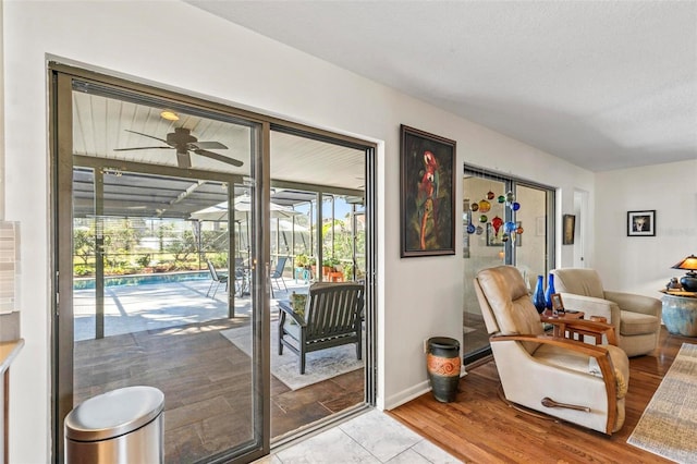 doorway to outside with light wood-type flooring, a textured ceiling, and ceiling fan