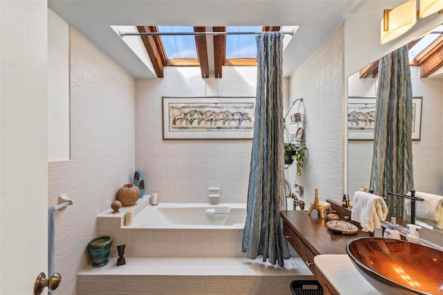 bathroom featuring tiled bath, tile walls, and vanity