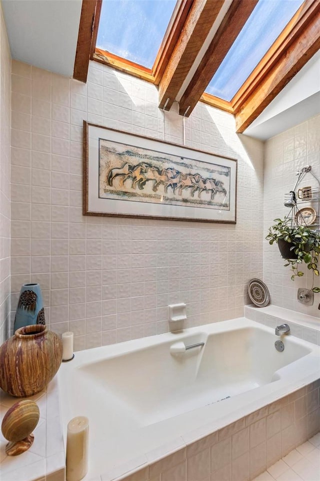 bathroom featuring tiled bath, tile walls, and a skylight