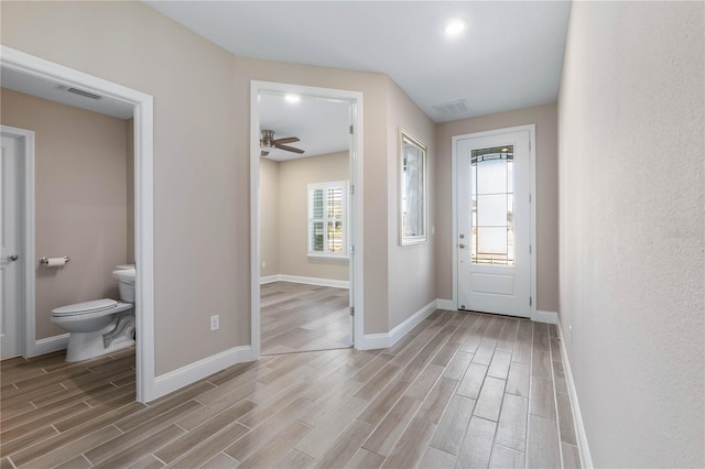 foyer with baseboards, visible vents, and wood finish floors