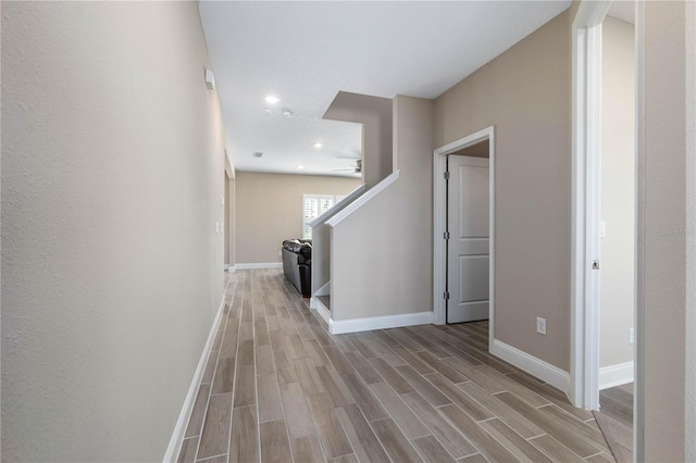 corridor with recessed lighting, stairs, baseboards, and wood finish floors