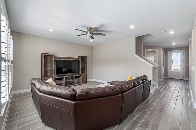 living area with recessed lighting, a ceiling fan, wood tiled floor, baseboards, and stairs