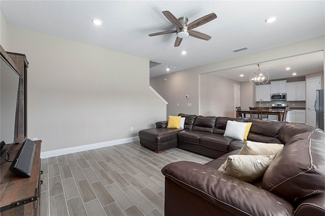 living room featuring recessed lighting, visible vents, baseboards, and ceiling fan with notable chandelier