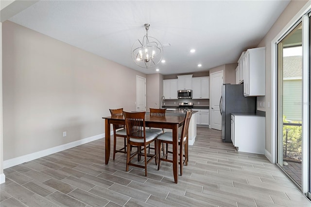 dining area with an inviting chandelier, wood tiled floor, baseboards, and recessed lighting