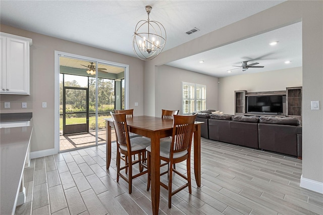 dining space featuring wood finish floors, visible vents, baseboards, and ceiling fan with notable chandelier