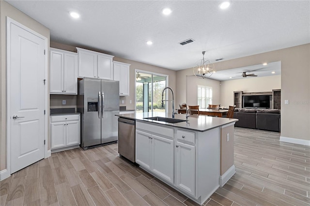 kitchen featuring a sink, white cabinetry, open floor plan, appliances with stainless steel finishes, and an island with sink