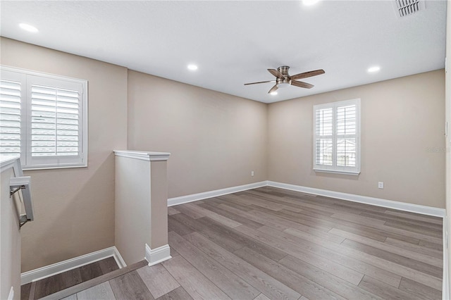 empty room featuring light wood-style flooring, recessed lighting, a ceiling fan, visible vents, and baseboards