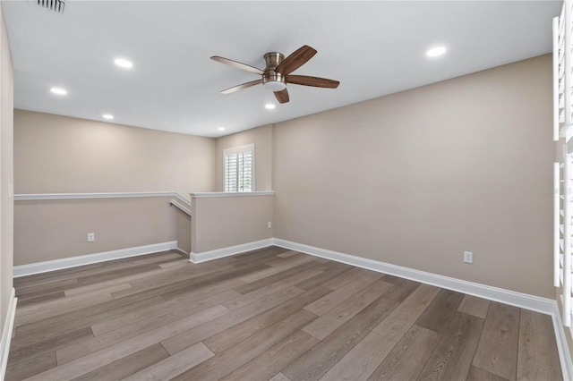 spare room featuring light wood finished floors, recessed lighting, a ceiling fan, and baseboards