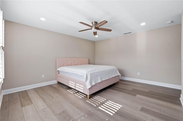 unfurnished bedroom with a ceiling fan, visible vents, light wood-style flooring, and baseboards