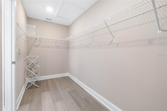 spacious closet with attic access, visible vents, and wood finished floors