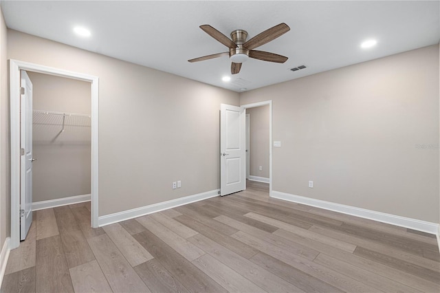 unfurnished bedroom featuring baseboards, visible vents, a spacious closet, light wood-style floors, and recessed lighting