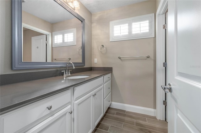 bathroom featuring wood finish floors, vanity, and baseboards